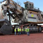 "The world’s biggest mining excavator Liebherr R9800 with workers next to it"